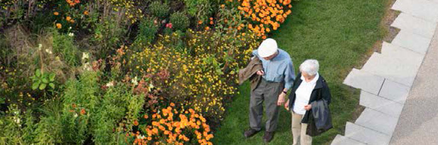 LONG-TERM CARE Image showing older couple walking in part looking at flowers.